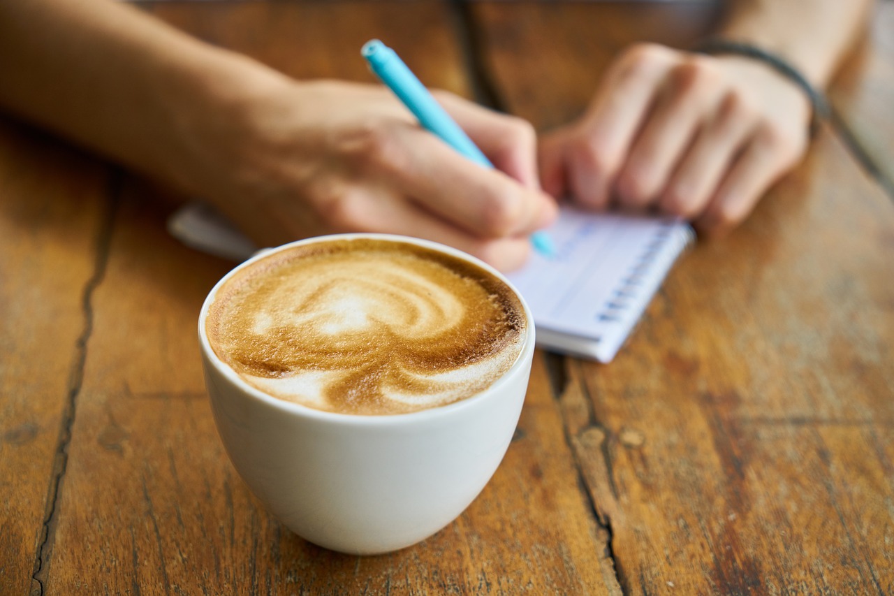 A person with a coffee writes a list of content ideas to include in her editorial calendar.