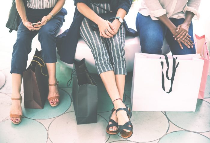 Three people with shopping bags sit on a bench. Talking to customers is a great way to find content ideas to put in your editorial calendar.