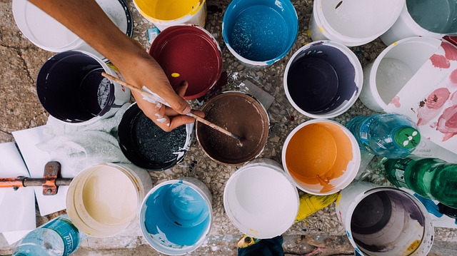 An image of tins of paint and someone painting, symbolising the need to continually update and improve your content.