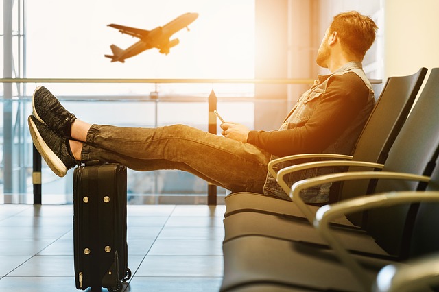 A guy in an airport watches a plane take off.