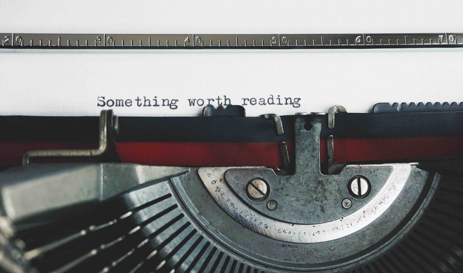 A typewriter with "something worth reading" typed on the paper, symbolising the value a manuscript proofreader brings to an author's writing.