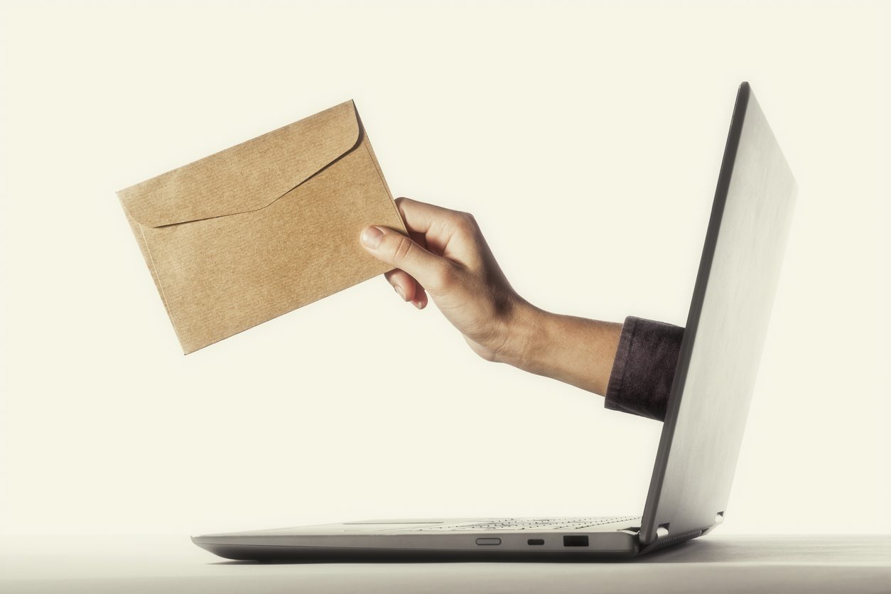 A hand holding an envelope reaches out of a laptop, symbolising Typeset's proofreading service for newsletters and electronic direct mail.